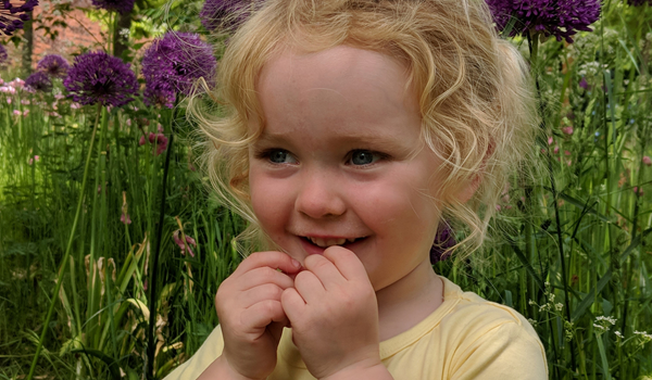 a little girl sitting in a garden